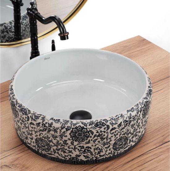 Lavabo blanc à motif floral bleu et blanc et robinet noir sur meuble en bois.