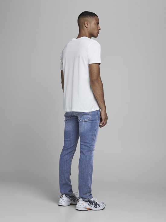 Man in een spijkerbroek met lichte wassing en een witte t-shirt.