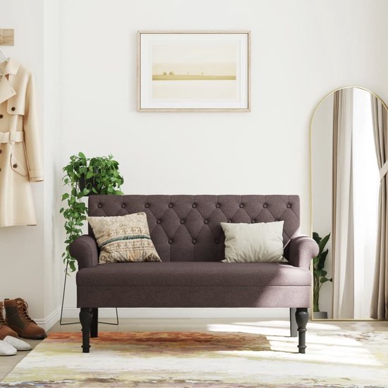 Donkerbruin bankje met knopen, gestyled in een hal met kleding en planten.