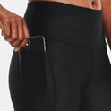 Close-up van de zijkant van een vrouw die een telefoon in het zijvak van een zwarte capri sportbroek plaatst.