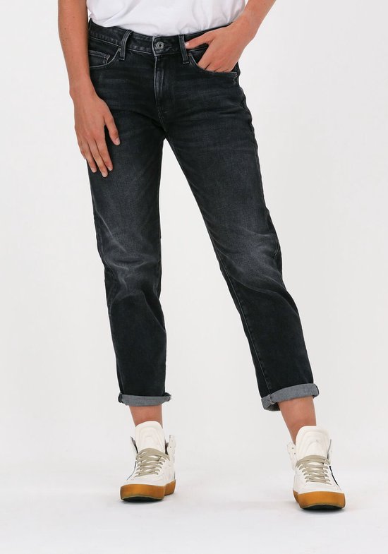 Een vrouw draagt een grijze G-Star Raw boyfriend jeans met omgerolde pijpen en witte sneakers.