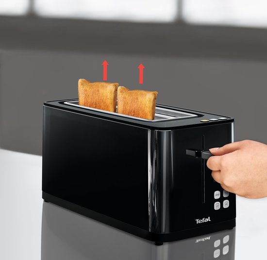 Une main actionne le levier d'un grille-pain Tefal noir, avec deux tranches de pain grillé sortant.