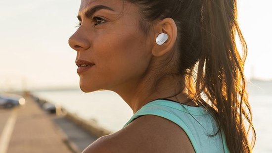 Zijprofiel van een vrouw die sport met een wit Belkin oordopje in haar oor.