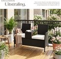 Zwarte polyrattan tuinbank met beige kussens, gedecoreerd met een plaid, op een balkon.