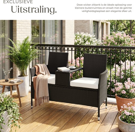 Zwarte polyrattan tuinbank met beige kussens, gedecoreerd met een plaid, op een balkon.
