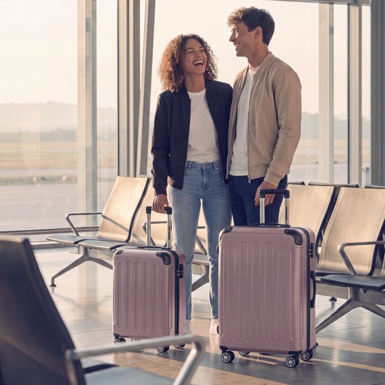 Een man en vrouw met roze koffers in een wachtruimte op de luchthaven.