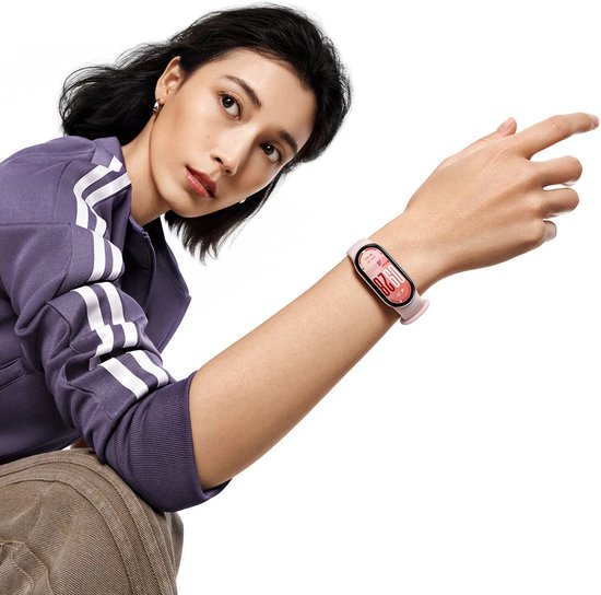 Femme en veste de sport violette portant un tracker d'activité rose clair au poignet.