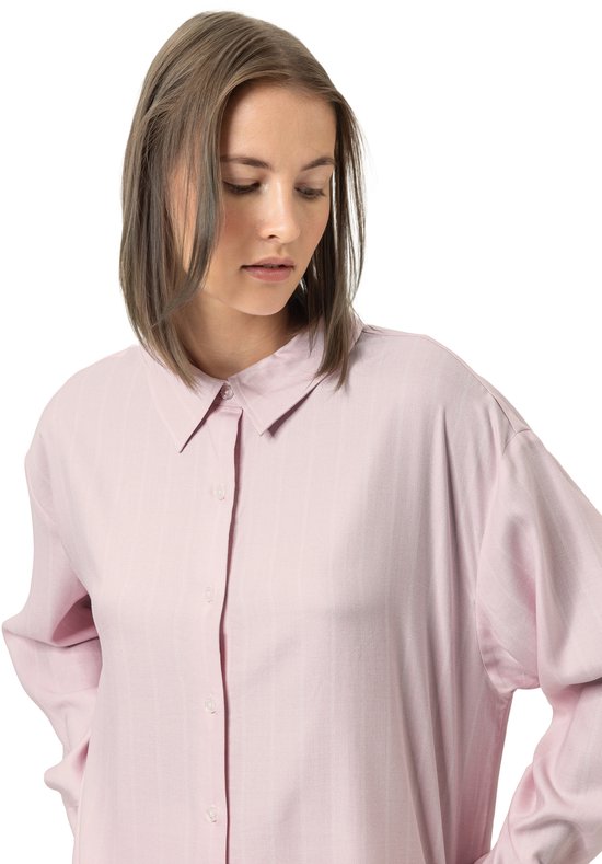 Model met halflang haar draagt een roze pyjamashirt met knoopsluiting en subtiele verticale strepen.