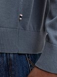 Detail van de onderkant van een donkerblauwe gebreide poloshirt met een klein label.