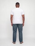 Man met korte mouwen wit T-shirt en blauwe relaxed fit jeans, van achteren gezien.