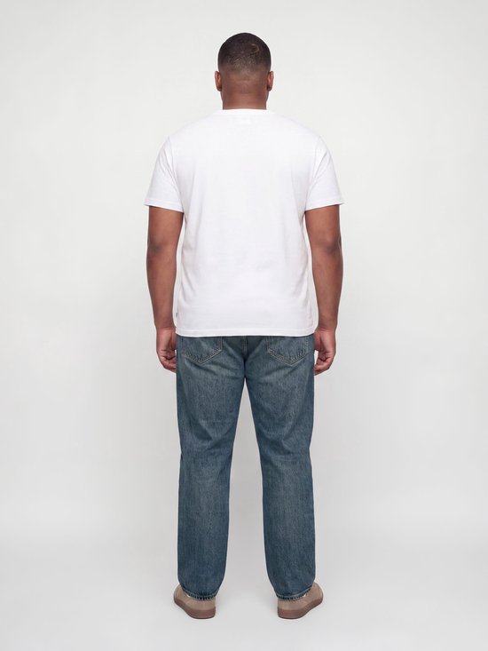 Man met korte mouwen wit T-shirt en blauwe relaxed fit jeans, van achteren gezien.