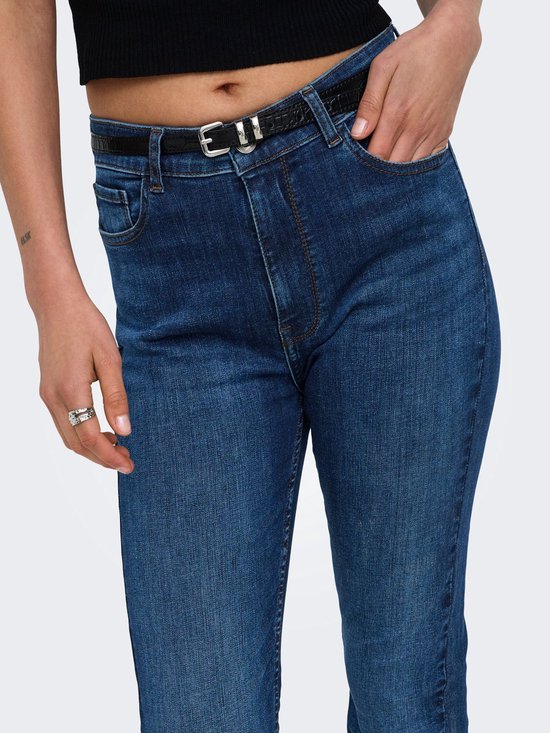 Close-up van een donkerblauwe slim fit jeans met een zwarte riem en hand in de zak.