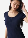Model draagt een donkerblauwe geribbelde nachtjapon met knoopjes bij de ronde hals en korte mouwen met ruches.