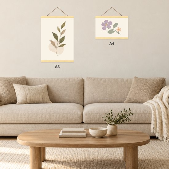 Woonkamer met twee aan de muur opgehangen posters in A3 en A4 formaat met houten hangers.