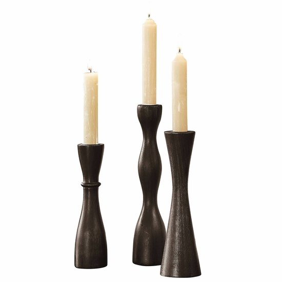 Ensemble de trois chandeliers noirs en bois aux formes torsadées variées. Deux chandeliers sont identiques, celui du milieu est plus haut avec un design ondulé.