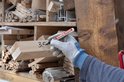 Hand met witte handschoen schrijft 3,5 met edding 3000 stift op houten balk.