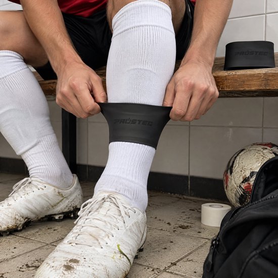 Voetballer trekt zwarte siliconen Prostec scheenbeschermer-band om zijn witte voetbalsokken.