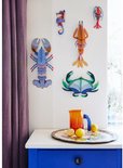 Decoratie van zeeschelp, krab, kreeft en garnaal aan een muur met een bijzettafel met fruitschaal.