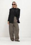 Model draagt zwarte, nauwsluitende ribgebreide longsleeve met een zwarte blazer.