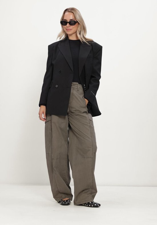 Model draagt zwarte, nauwsluitende ribgebreide longsleeve met een zwarte blazer.