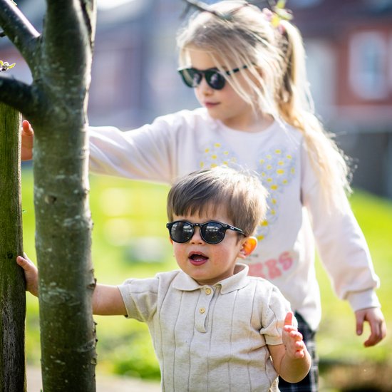 Jongen en meisje met zwarte zonnebrillen in de tuin.