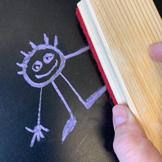 Une brosse en bois avec un bord rouge efface un dessin violet sur un tableau noir.