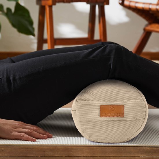 Een beige yogabolster met een corduroy textuur, die door een vrouw wordt gebruikt voor een rugoefening.