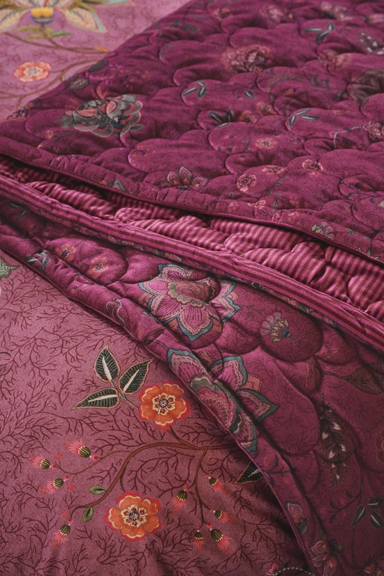 Gedetailleerd paars sprei met bloemenprint en strepen. Veelkleurige bloemen en paisley patronen.