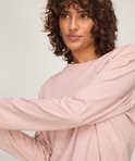 Close-up van een zachtroze longsleeve pyjamatop met een klein geborduurd hartje op de linkerborst.
