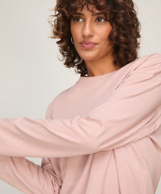 Close-up van een zachtroze longsleeve pyjamatop met een klein geborduurd hartje op de linkerborst.