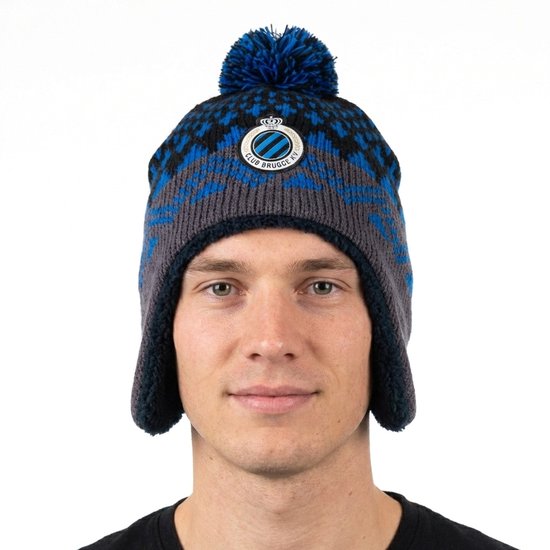 Vooraanzicht van een Club Brugge muts in grijs en blauw met oorflappen, logo en blauwe pompon.