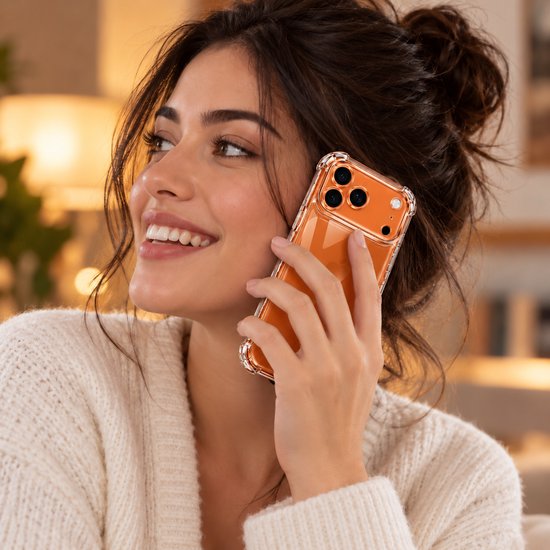 Vrouw met knotje belt met een transparant oranje YSONIC schokbestendig hoesje voor iPhone 17 Pro.