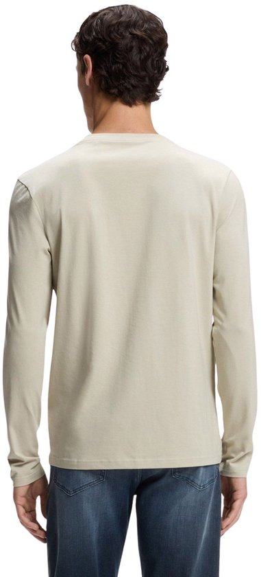 De achterkant van een model dat een beige shirt met lange mouwen en een blauwe jeans draagt.