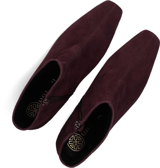 Bovenaanzicht van twee donkerpaarse suède enkelboots met rits en goudkleurig Unisa-logo op de binnenzool.