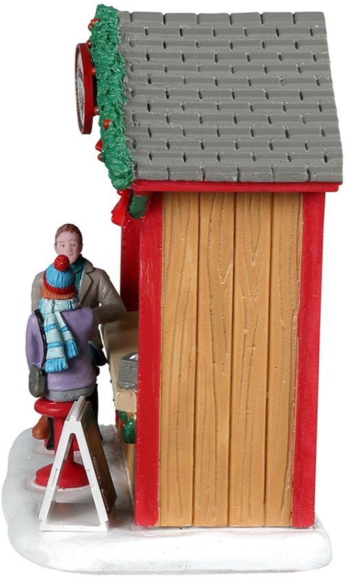 Zijaanzicht van een houten kerstcafé-kraam, versierd met groen, op een besneeuwde ondergrond.