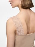 Detailopname van een beige hemdje met kanten schouderbandjes op een model.