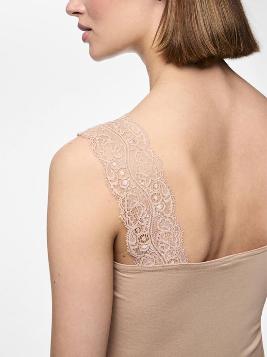 Detailopname van een beige hemdje met kanten schouderbandjes op een model.
