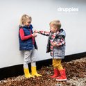 Jongen en meisje met gele en rode Druppies laarzen in de herfst.