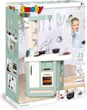 Doos van de Smoby Cherry speelkeuken met een jongen die er vrolijk naar kijkt en 25 accessoires.