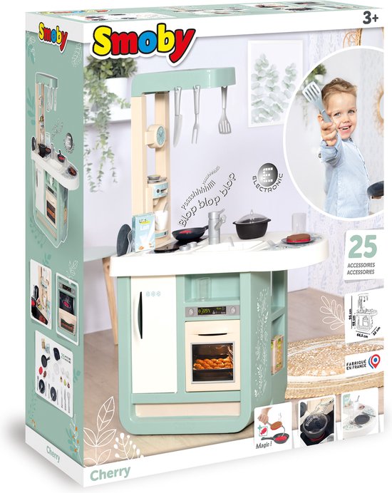 Doos van de Smoby Cherry speelkeuken met een jongen die er vrolijk naar kijkt en 25 accessoires.