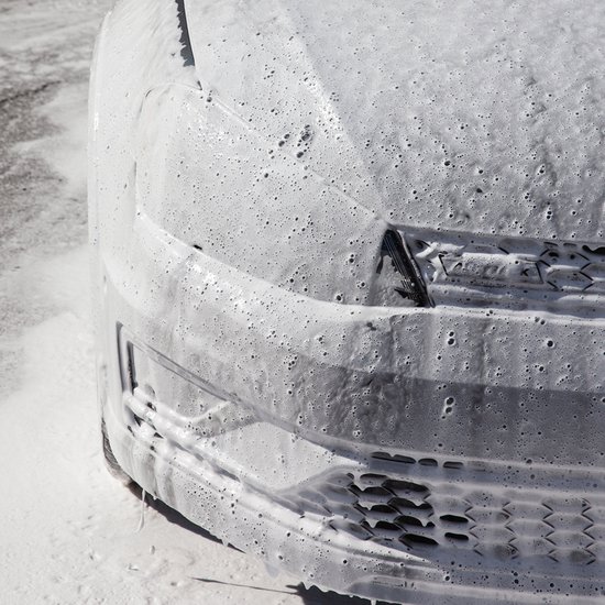 Voorkant van een auto bedekt met dicht Turtle Wax Snow Foam.