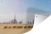 Muurdecoratie Kamelen die in de woestijn voor Dubai langslopen - 180x120 cm - Tuinposter - Tuindoek - Buitenposter