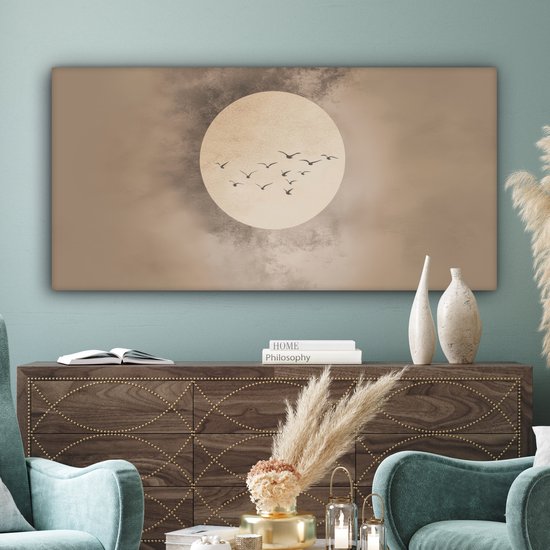 Canvas schilderij met beige tinten, zachte cirkel en vogels, boven een donkerhouten kast.