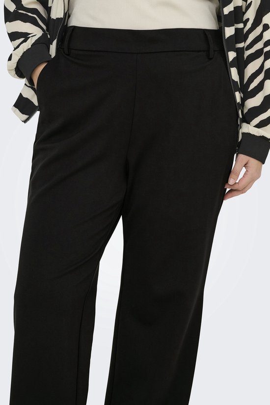 Close-up van de heupen van een model in een zwarte wijde broek en een jasje met zebraprint.