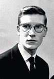 Portret van een jonge Yves Saint Laurent met bril en pak.