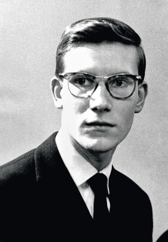 Portret van een jonge Yves Saint Laurent met bril en pak.