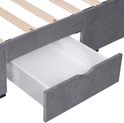 Detail van een open opberglade van een grijs gestoffeerd bedframe, met houten lattenbodem.