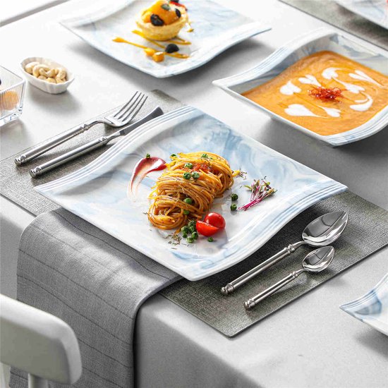 Tafelsetting met marmerblauwe borden. Een bord met spaghetti, een bord met dessert, een bord met pompoensoep, en een kopje koffie.
