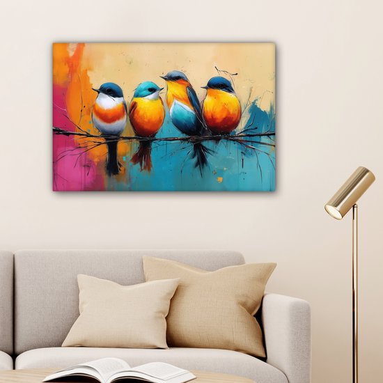 Vier kleurrijke vogels op een tak, hangend aan een muur boven een bank. De achtergrond is een abstracte mix van oranje, roze, blauw en geel. Een staande lamp staat rechts.