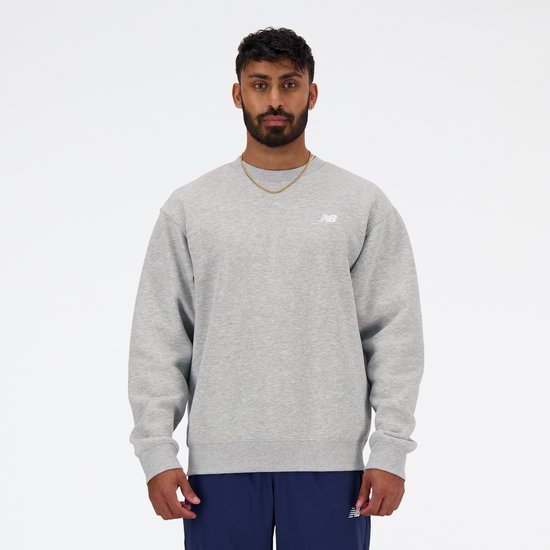 Man met grijze New Balance sweater met wit logo, gouden ketting.